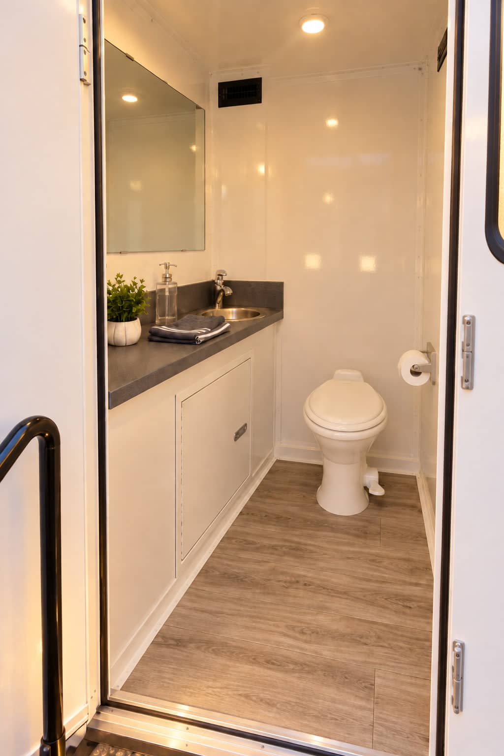 Inside one stall, with a flushing toilet, a basin on a stone counter, a mirror and folded towels